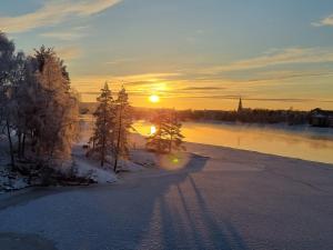 una puesta de sol sobre un río con nieve en el suelo en Polaris Homes for You, en Rovaniemi