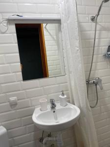 een witte badkamer met een wastafel en een spiegel bij Nazar Stodolya in Kamjanets-Podilsky
