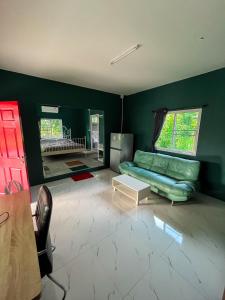 uma sala de estar com um sofá verde e uma mesa em North Pine Forest Homestay บ้านไม้สนโฮมสเตย์ em Ban Mae Pong