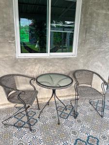 een tafel en twee stoelen en een tafel en twee ramen bij North Pine Forest Homestay บ้านไม้สนโฮมสเตย์ in Ban Mae Pong