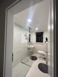 a white bathroom with a shower and a sink at Kiefern Apartments in Hannover