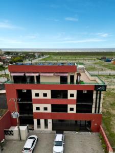 un estacionamiento con autos estacionados frente a un edificio en Hotel Amaromar, en Pontal do Paraná