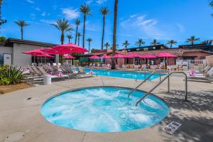 a swimming pool with chairs and pink umbrellas at The Paloma Resort in Palm Springs