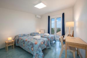 a bedroom with two beds and a table and a desk at Villette Orsa Maggiore in Pozzallo