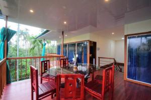 a dining room with a glass table and red chairs at Greens Vista Wayanad - Premium Homestay Near Natural Stream in Panamaram