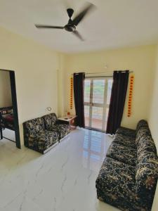 sala de estar con 2 sofás y ventilador de techo en The Peacewood's Homes - Pune's Comfort - Hostel & PG, en Pune