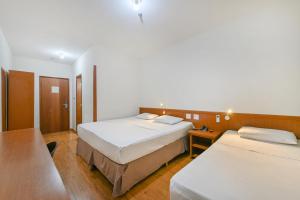 リメイラにあるHotel Nacional Inn Limeiraのベッド2台とテーブルが備わるホテルルームです。