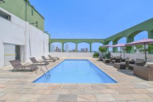 una piscina en un edificio con sillas y sombrillas en Hotel Nacional Inn Limeira en Limeira