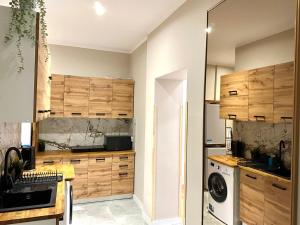 a kitchen with wooden cabinets and a washer and dryer at Spidey Room in Gdańsk