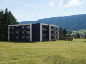 un bâtiment dans un champ avec une pelouse dans l'établissement Appartement 37m² avec balcon, 500m centre village et pistes ski, parking privé - Autrans - FR-1-737-40, à Autrans