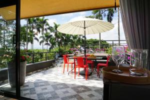 eine Terrasse mit einem Tisch, Stühlen und einem Sonnenschirm in der Unterkunft LALDEA Nirvana Eco Villa in Cerritos in Pereira