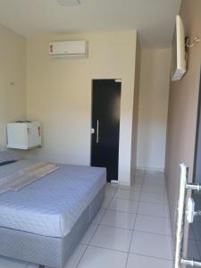 1 dormitorio con cama y puerta negra en Pousada das Acacias en Carananduba