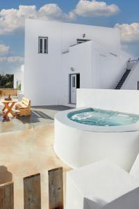 イメロヴィグリにあるAthiri Santorini Hotelのホットタブ付きのパティオが備わるホワイトハウスです。
