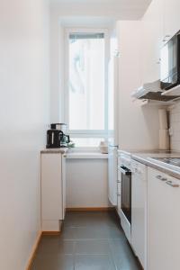 uma cozinha com armários brancos e uma janela em Scandic Primo Apartments - Malminkatu 49m2 em Helsinque