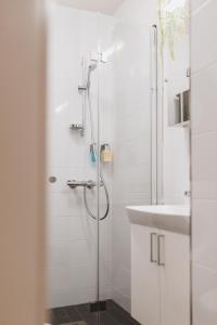 uma casa de banho branca com um chuveiro e um lavatório. em Scandic Primo Apartments - Malminkatu 49m2 em Helsinque