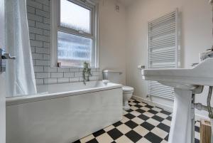 a bathroom with a tub and a sink and a toilet at 4 Bed Manor Design House, Modern, Spacious- Pet Friendly! Sleeps 9, Portsmouth - By Blue Puffin Stays in Portsmouth