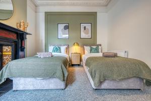 two beds sitting next to each other in a room at 4 Bed Manor Design House, Modern, Spacious- Pet Friendly! Sleeps 9, Portsmouth - By Blue Puffin Stays in Portsmouth