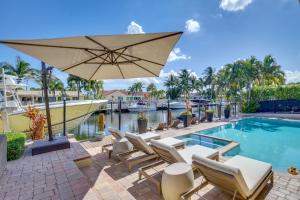 a pool with lounge chairs and an umbrella next to a swimming pool at Lighthouse Point Home with Pool and Canal Access in Lighthouse Point