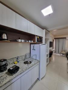 a kitchen with a sink and a white refrigerator at Spazzio diRoma in Caldas Novas