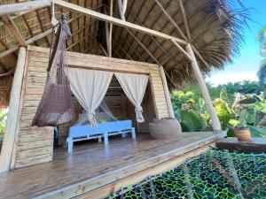 a hammock and a bench on a porch of a hut at Samana Ecolodge in El Limón