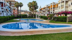 - une grande piscine dans une cour à côté de certains bâtiments dans l'établissement Laguna Beach Costasol - Alojamientos La Torre, à Torrox Costa