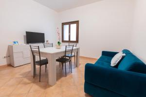 a living room with a table and chairs and a blue couch at Nuovi Appartamenti Tri e Bilocali in Residence con Piscina a Porto Cervo 800mt Mare in Liscia di Vacca