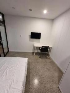 a white room with a desk and a television at Sydney Airport Guest House in Sydney