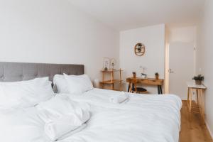 uma grande cama branca com lençóis e almofadas brancos em Scandic Primo Apartments - Design District 69m2 em Helsinque