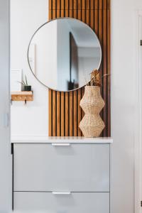 um espelho em cima de uma cómoda branca com um vaso em Scandic Primo Apartments - Design District 69m2 em Helsinque