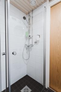 a shower in a bathroom with white tiles at Scandic Primo Apartments - Design District 69m2 in Helsinki