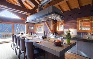 a large kitchen with a long island with a long table at Chalet Norma by Leavetown Vacations in Les Deux Alpes
