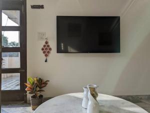 uma sala de estar com uma mesa e uma televisão na parede em Zel’s Stay by Six Lane em Sohāna