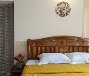 um quarto com uma cama de madeira e um cobertor amarelo em Zel’s Stay by Six Lane em Sohāna
