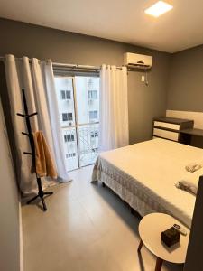 een slaapkamer met een bed en een groot raam bij Apartamento prox shopping atlântico BrisamarBC5 in Balneário Camboriú