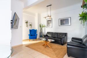 a living room with a black leather couch and a blue chair at Majestic 2 Glyfada in Athens