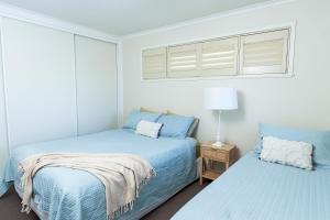 Un dormitorio con dos camas con sábanas azules y una ventana. en Toowoomba Hospital Apartments, en Rockville