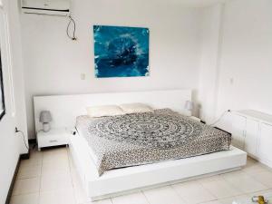 1 dormitorio blanco con 1 cama y una pintura en la pared en Las palmeras, en Playas