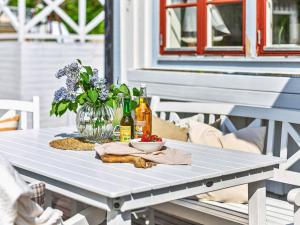Holiday home Ödsmål II في Ödsmål: طاولة بيضاء مع إناء من الزهور والمشروبات