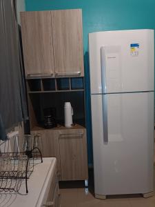 a kitchen with a white refrigerator and wooden cabinets at Hollydayhouse in Prudentópolis