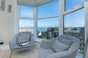 uma sala de estar com duas cadeiras e uma grande janela em Sea Salt sea views parking em St Ives