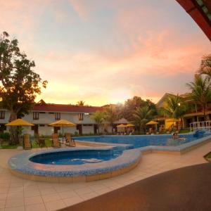a resort pool with a sunset in the background at Hotel Laguna Azul in Sauce