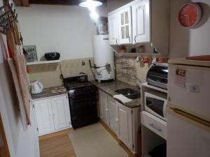 a small kitchen with white cabinets and black appliances at Cálido Departamento Céntrico San Martín de los andes in San Martín de los Andes
