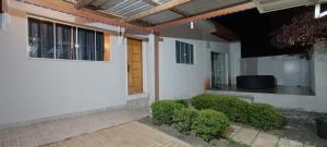 a white house with a door and some bushes at Hollydayhouse in Prudentópolis