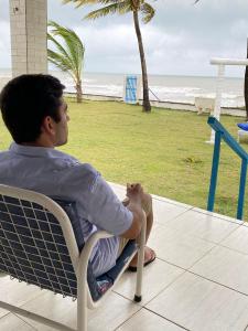 Un uomo seduto su una sedia che guarda la spiaggia di A 2 passos do paraíso a Rio Tinto