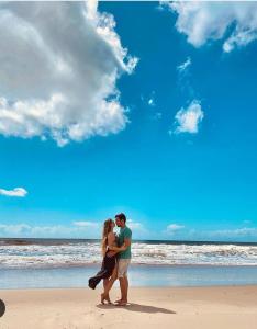 a man and a woman standing on a beach at A 2 passos do paraíso in Rio Tinto