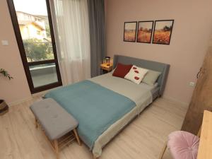 a bedroom with a bed with a chair and a window at Kalina Apartment Kazanlak in Kazanlŭk