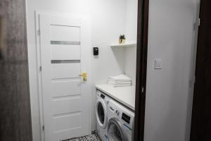 een wasruimte met een witte deur en een wasmachine bij CracWoW K8 No.9 Apartment in Krakau +18 foto's