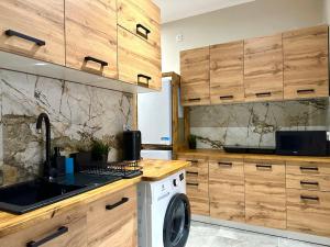 a kitchen with a washing machine and wooden cabinets at MMRent Paris Room in Gdańsk