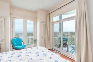- une chambre avec une chaise bleue et une grande fenêtre dans l'établissement Seascape on Harbor Island, à Oceanmarsh Subdivision