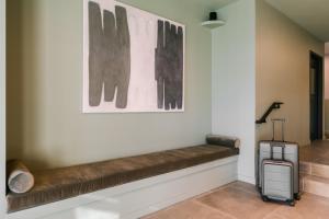 a bench in a hallway with a painting and a suitcase at Placemakr NoMa in Washington, D.C.